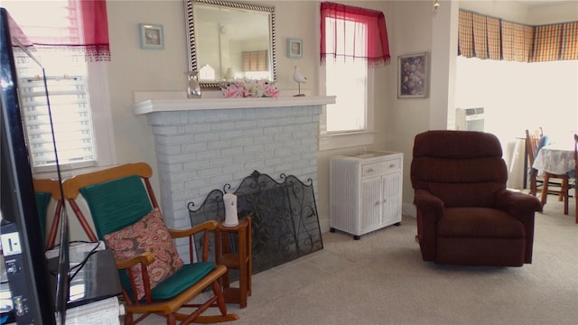 living area with a brick fireplace, a wealth of natural light, and carpet