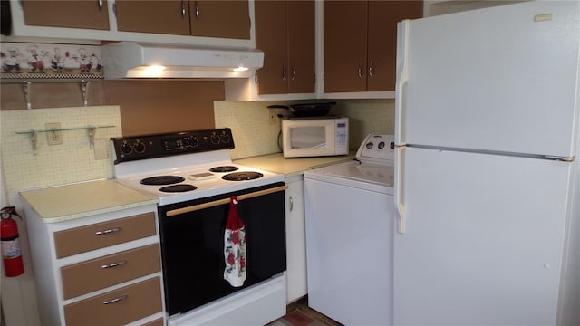 kitchen with backsplash, white appliances, washer / dryer, and custom range hood