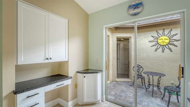 kitchen with white cabinetry, built in desk, and light tile patterned flooring