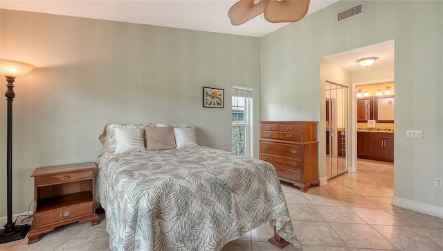 bedroom with ensuite bath, light tile patterned floors, and ceiling fan