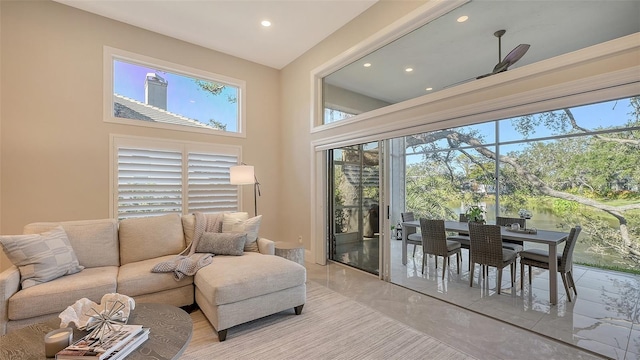 living room with ceiling fan, a wealth of natural light, and a towering ceiling