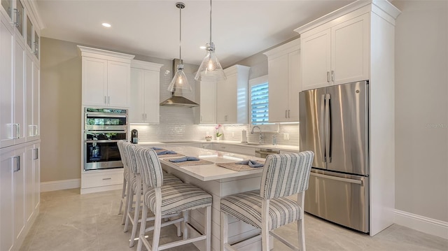 kitchen featuring wall chimney range hood, white cabinets, and stainless steel appliances