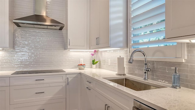 kitchen with sink, white cabinets, black electric cooktop, and wall chimney range hood