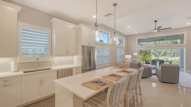 kitchen featuring a breakfast bar, decorative backsplash, sink, stainless steel appliances, and white cabinets