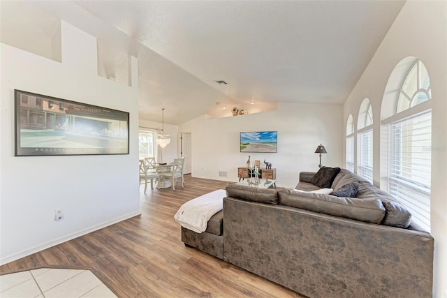 living room with wood-type flooring, lofted ceiling, and a notable chandelier