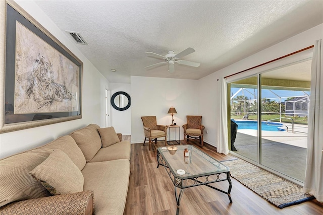 living room featuring hardwood / wood-style floors, a textured ceiling, and ceiling fan