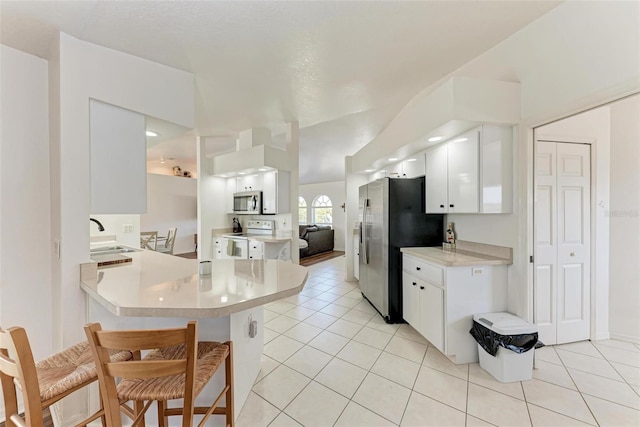 kitchen with sink, stainless steel appliances, light tile patterned floors, kitchen peninsula, and white cabinets