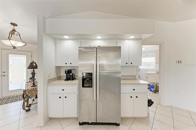 kitchen featuring stainless steel fridge, light tile patterned floors, white cabinetry, and hanging light fixtures