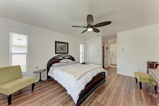 bedroom featuring ensuite bath, ceiling fan, hardwood / wood-style floors, and multiple windows