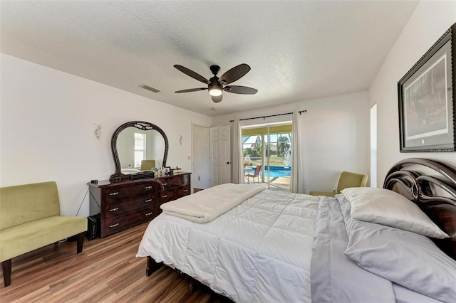 bedroom featuring hardwood / wood-style flooring, ceiling fan, access to exterior, and a textured ceiling