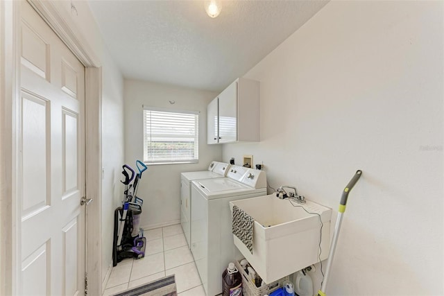 laundry area with sink, light tile patterned floors, a textured ceiling, and washing machine and clothes dryer