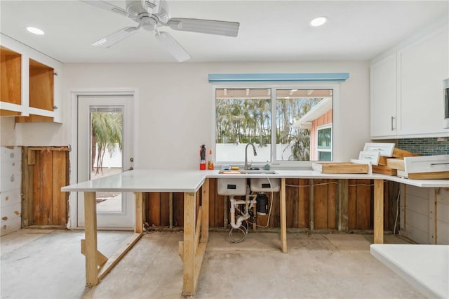 kitchen with ceiling fan, sink, white cabinets, and backsplash