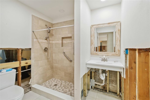 bathroom featuring tile patterned floors, toilet, sink, and a tile shower