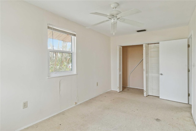 unfurnished bedroom featuring light colored carpet, ceiling fan, and a closet