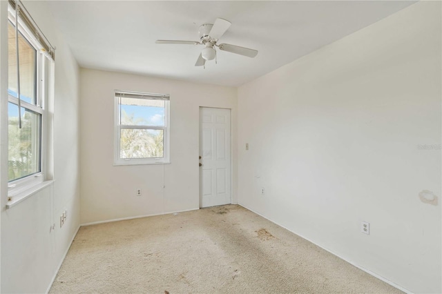 carpeted empty room featuring ceiling fan and a healthy amount of sunlight