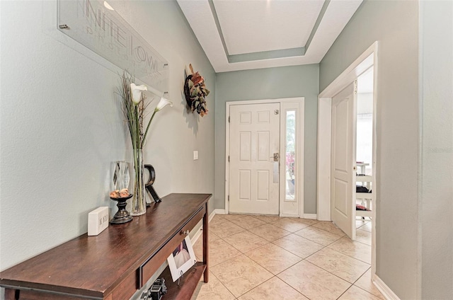 foyer entrance featuring a raised ceiling and light tile patterned floors