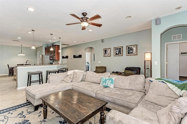 living room with ceiling fan, a textured ceiling, sink, and light tile patterned floors