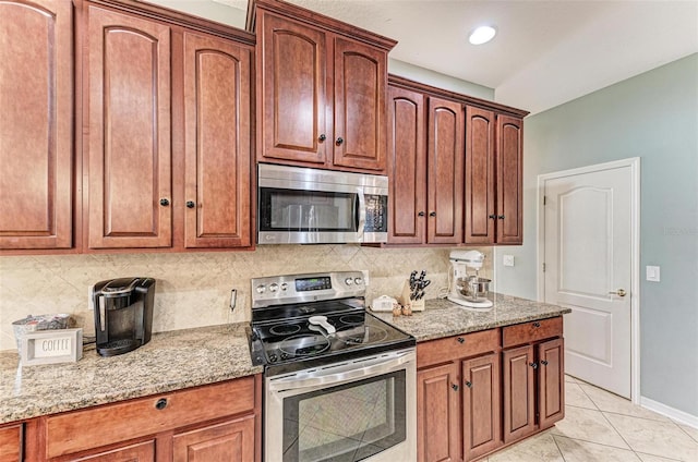 kitchen featuring tasteful backsplash, stainless steel appliances, light stone countertops, and light tile patterned floors