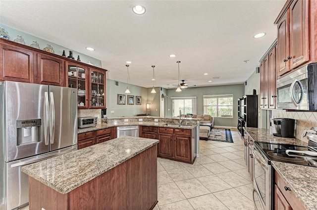 kitchen featuring appliances with stainless steel finishes, ceiling fan, pendant lighting, decorative backsplash, and sink