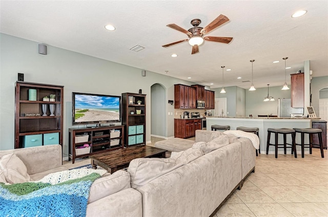 living room featuring ceiling fan, a textured ceiling, and light tile patterned floors