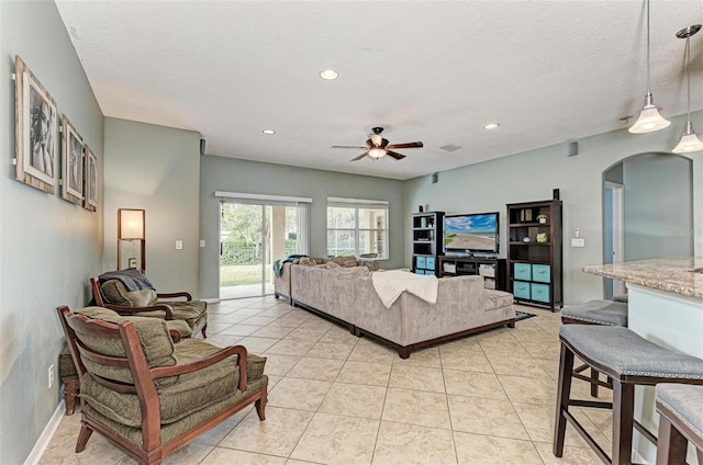 living room featuring ceiling fan, light tile patterned floors, and a textured ceiling