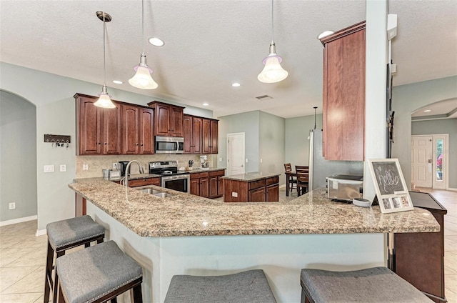 kitchen with sink, hanging light fixtures, kitchen peninsula, and appliances with stainless steel finishes