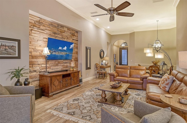 living room featuring ceiling fan with notable chandelier, light hardwood / wood-style flooring, and ornamental molding