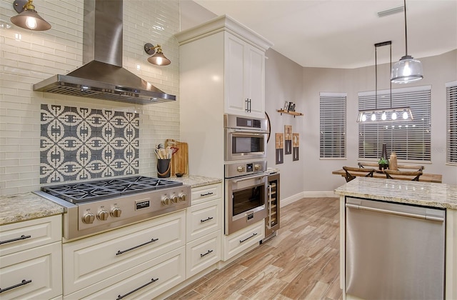 kitchen with light stone countertops, backsplash, appliances with stainless steel finishes, and ventilation hood