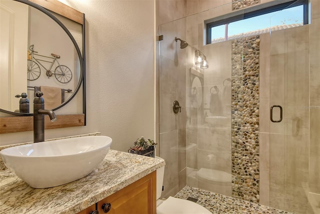 bathroom featuring a shower with shower door, vanity, and toilet