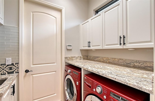 clothes washing area with separate washer and dryer and cabinets