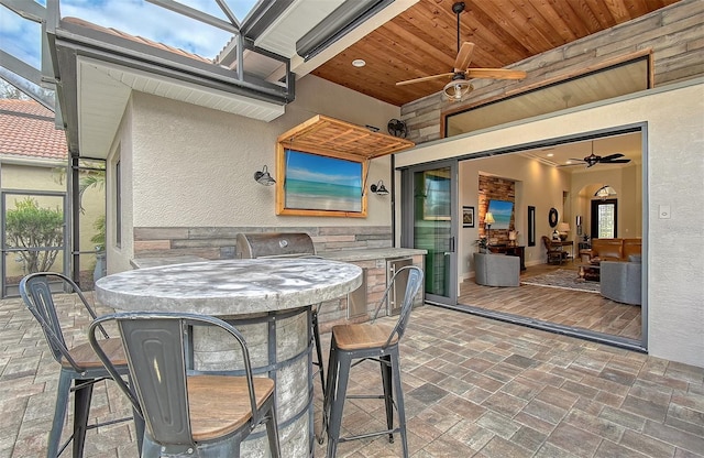 view of patio with a lanai, ceiling fan, and exterior bar