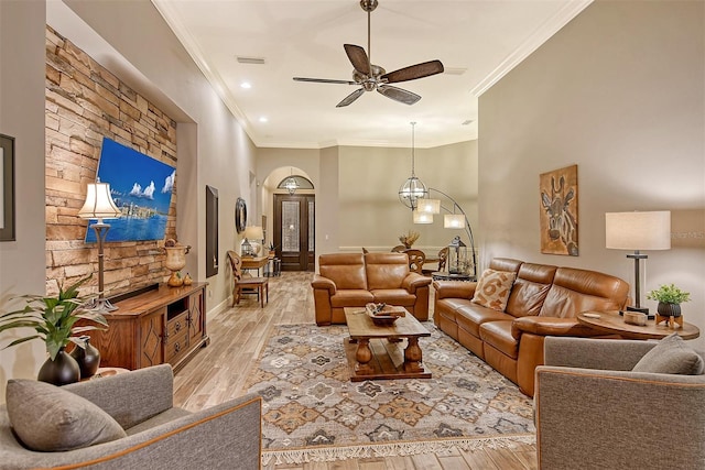 living room with ceiling fan with notable chandelier, light hardwood / wood-style flooring, and crown molding