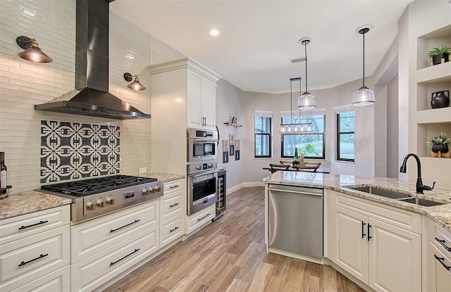 kitchen featuring exhaust hood, sink, light stone countertops, stainless steel appliances, and white cabinets