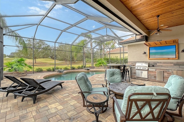 view of patio with ceiling fan, a grill, exterior kitchen, glass enclosure, and an outdoor bar