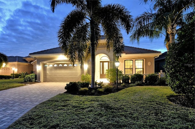 mediterranean / spanish home with a garage and a lawn