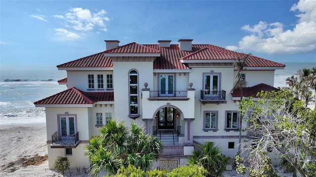 rear view of house with a water view, french doors, and a balcony