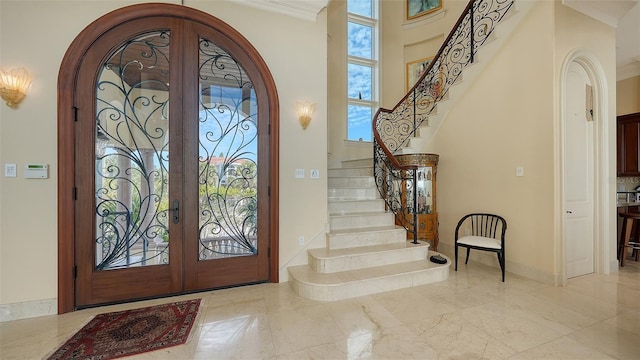 foyer entrance featuring plenty of natural light, crown molding, and french doors