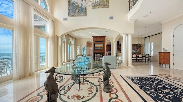 entryway featuring crown molding, a water view, a high ceiling, and decorative columns