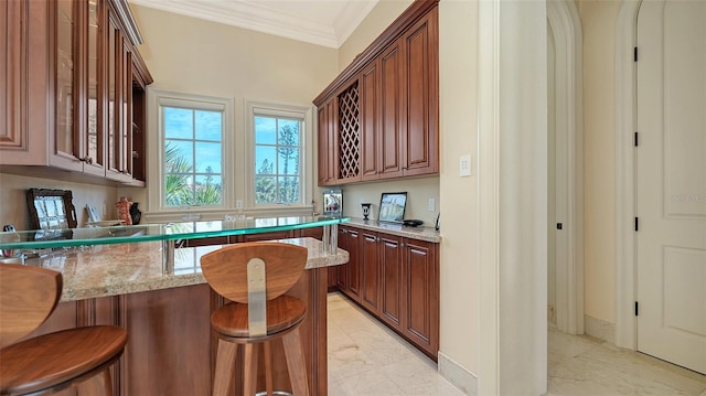 kitchen with crown molding, a breakfast bar, and light stone countertops