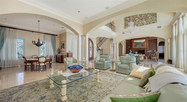 living room with ornamental molding, a chandelier, and decorative columns