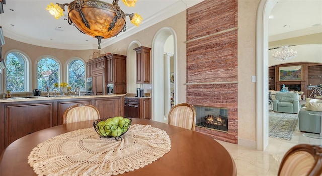 dining room with a large fireplace, crown molding, and a notable chandelier