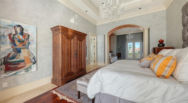 bedroom with a tray ceiling, crown molding, light wood-type flooring, a chandelier, and decorative columns