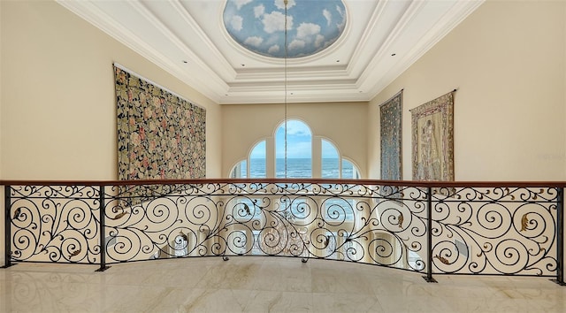 corridor with ornamental molding, a water view, and a tray ceiling