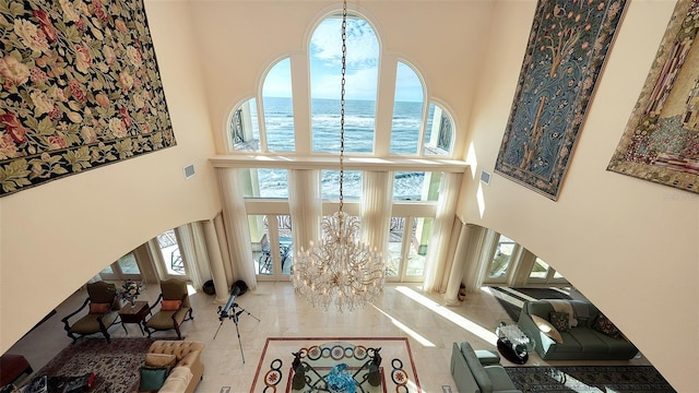 living room featuring a towering ceiling, a water view, and an inviting chandelier