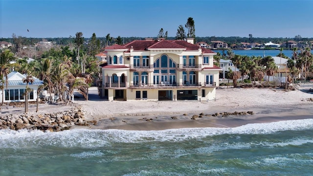 back of house featuring a water view, a beach view, and a balcony