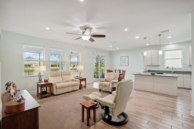 living room featuring ceiling fan, light hardwood / wood-style floors, and sink