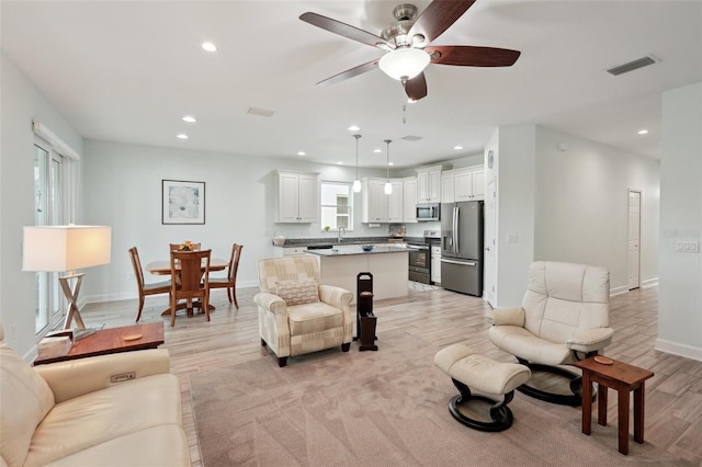 living room with ceiling fan and light hardwood / wood-style flooring