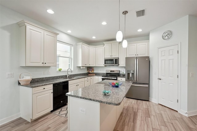 kitchen with appliances with stainless steel finishes, a kitchen island, a kitchen bar, decorative light fixtures, and sink