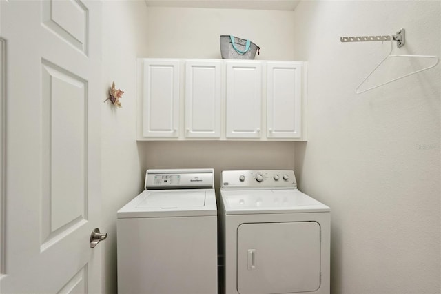 laundry room with washing machine and dryer and cabinets