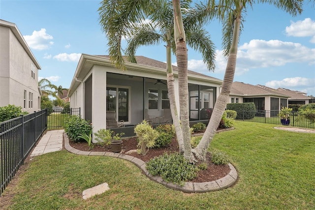 rear view of house featuring ceiling fan, a sunroom, and a lawn